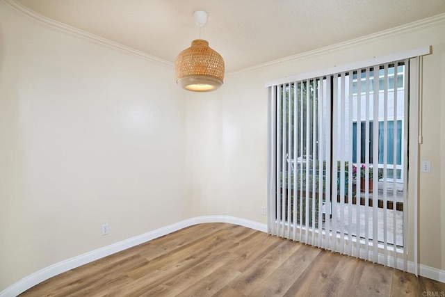 spare room with baseboards, ornamental molding, and wood finished floors