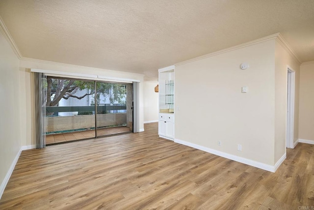 unfurnished room featuring light wood finished floors, crown molding, and a textured ceiling