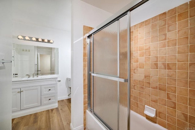 bathroom with combined bath / shower with glass door, wood finished floors, and vanity