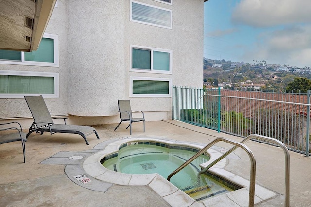 view of swimming pool featuring a hot tub, fence, and a patio