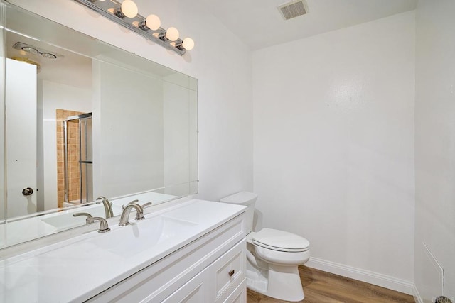 full bath with visible vents, toilet, vanity, wood finished floors, and baseboards