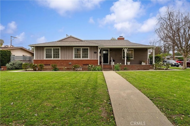 ranch-style house with a chimney, a front lawn, board and batten siding, and brick siding