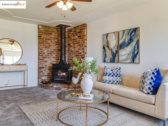 carpeted living room with ceiling fan and a wood stove