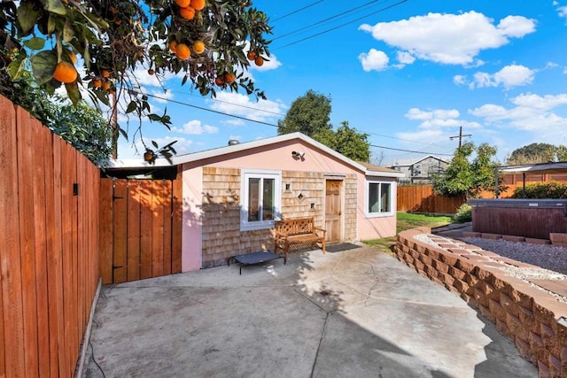 back of house with a hot tub and a patio