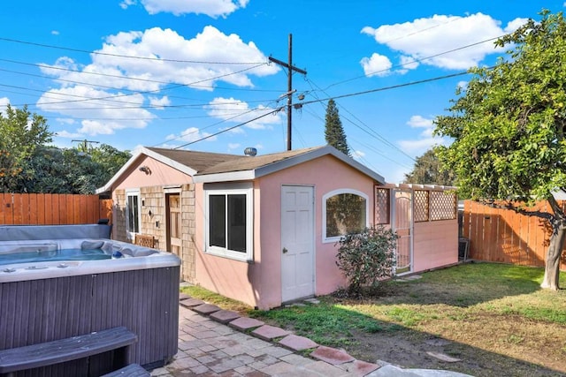 exterior space with a hot tub and a yard