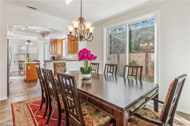 dining area featuring a raised ceiling, sink, ceiling fan with notable chandelier, and ornamental molding