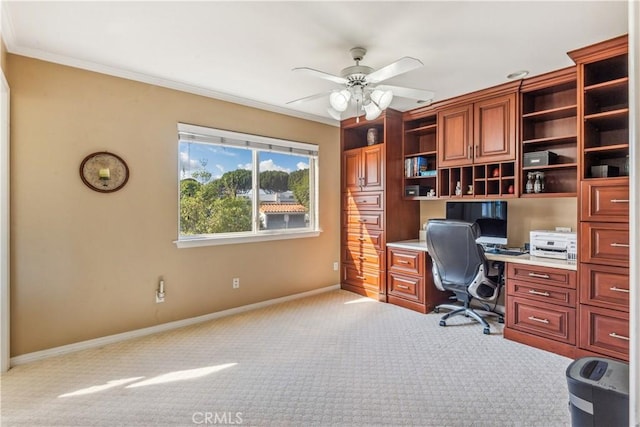 office space featuring built in desk, light colored carpet, ceiling fan, and ornamental molding