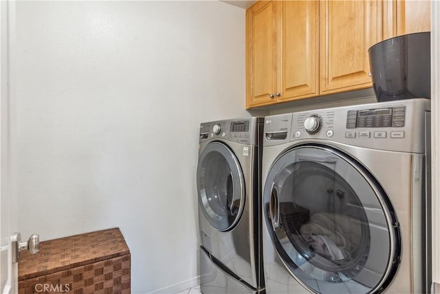 clothes washing area featuring washing machine and dryer and cabinets