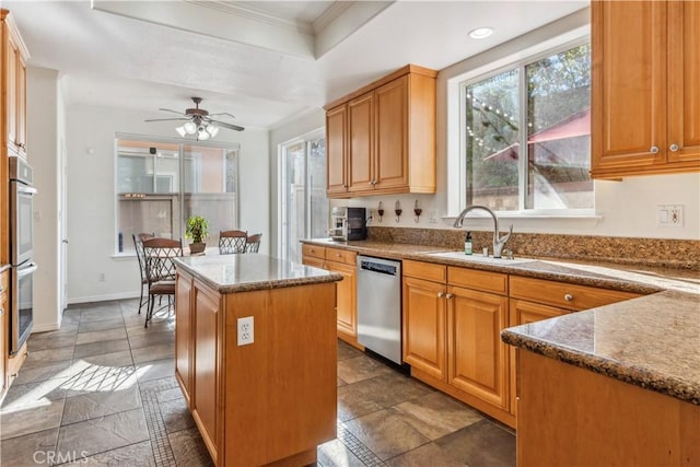 kitchen featuring ceiling fan, appliances with stainless steel finishes, a center island, ornamental molding, and sink