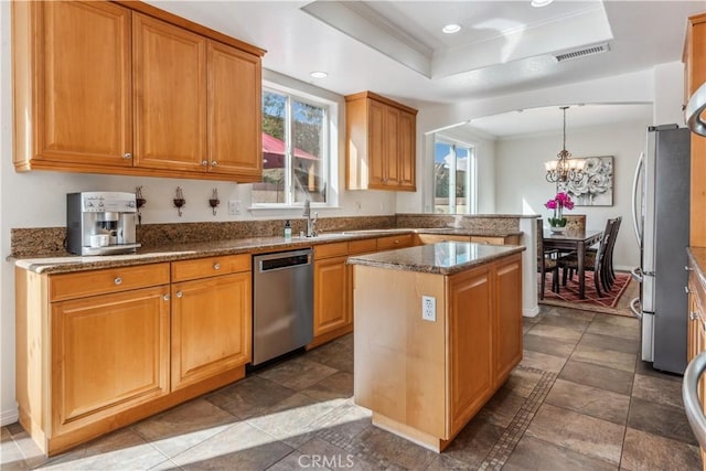 kitchen with a kitchen island, pendant lighting, a tray ceiling, appliances with stainless steel finishes, and a chandelier