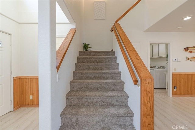 staircase featuring wooden walls, separate washer and dryer, and hardwood / wood-style flooring