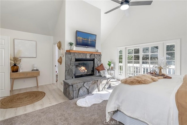 bedroom featuring ceiling fan, a stone fireplace, and high vaulted ceiling