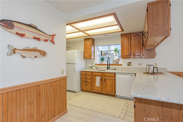 kitchen featuring light stone countertops, sink, white appliances, and wooden walls