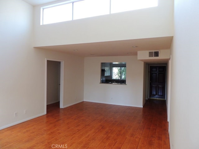 unfurnished living room with hardwood / wood-style flooring and a towering ceiling