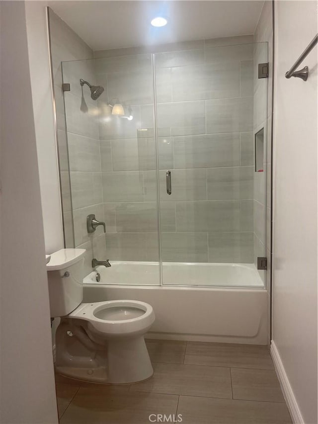 bathroom with toilet, tile patterned flooring, and combined bath / shower with glass door