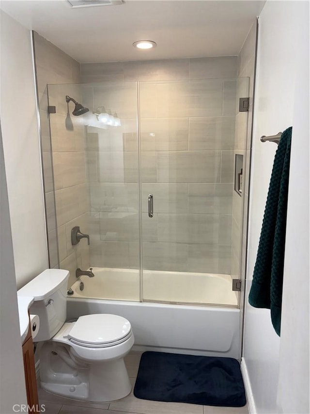 bathroom with combined bath / shower with glass door, tile patterned floors, and toilet