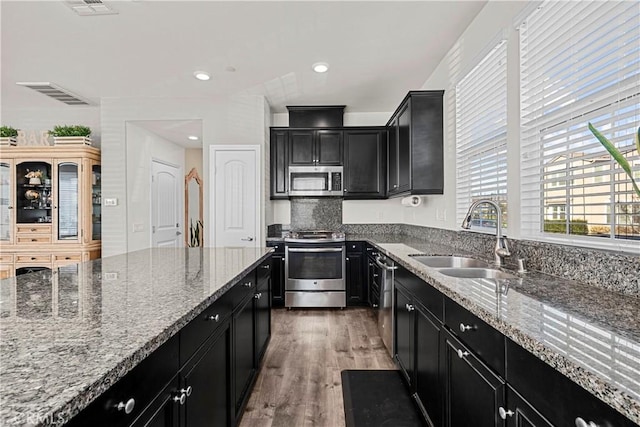 kitchen featuring light stone countertops, sink, appliances with stainless steel finishes, and dark wood-type flooring