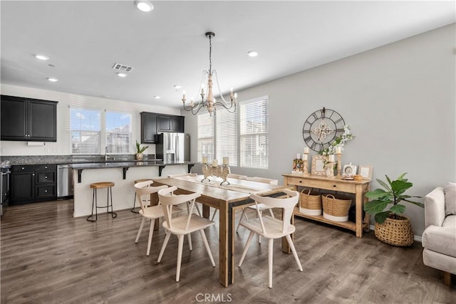 dining area featuring dark wood-type flooring, plenty of natural light, and a notable chandelier