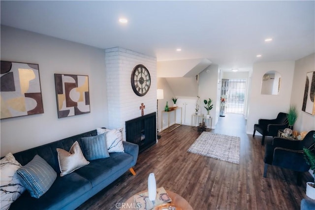 living room featuring dark hardwood / wood-style flooring and a brick fireplace