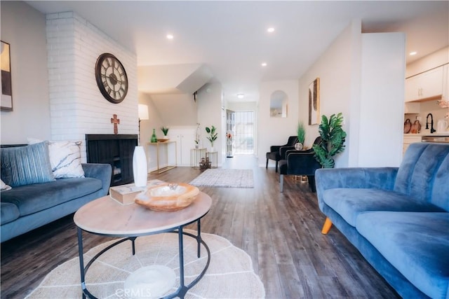 living room featuring dark hardwood / wood-style flooring, sink, and a brick fireplace