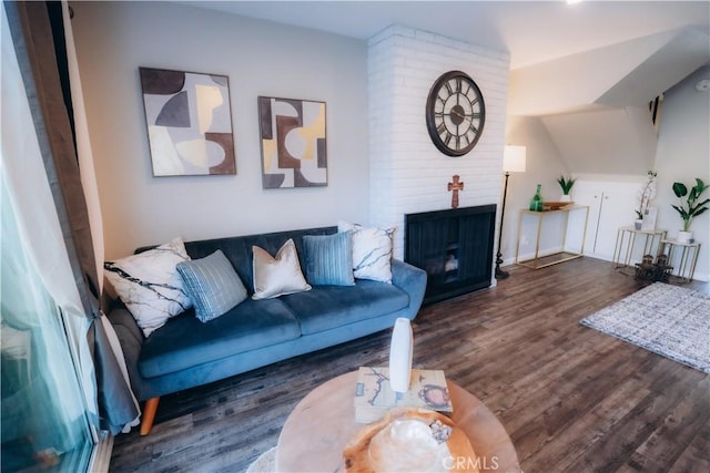 living room featuring a brick fireplace and dark hardwood / wood-style floors