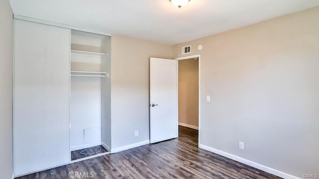 unfurnished bedroom featuring dark hardwood / wood-style floors and a closet