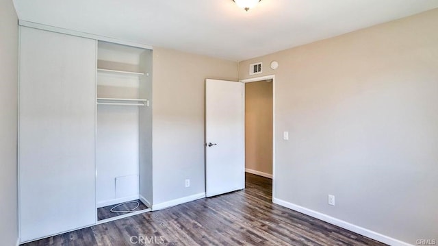 unfurnished bedroom with dark hardwood / wood-style floors and a closet