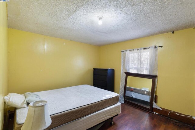 bedroom with a textured ceiling and dark hardwood / wood-style flooring