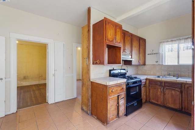 kitchen featuring sink, black range with gas stovetop, backsplash, tile counters, and light tile patterned floors