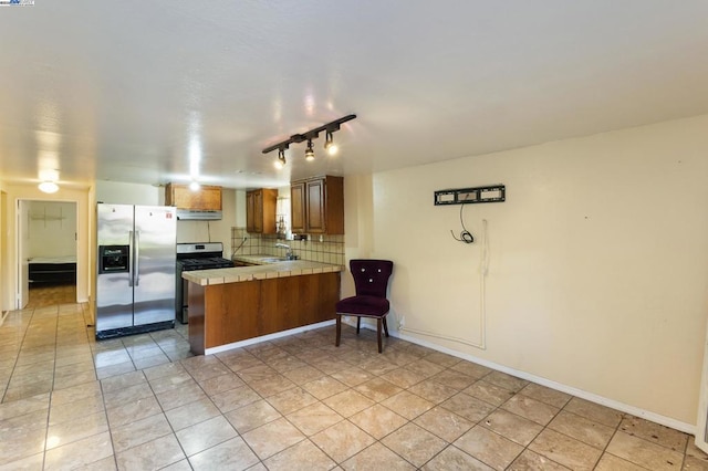 kitchen with sink, stainless steel appliances, decorative backsplash, tile countertops, and kitchen peninsula