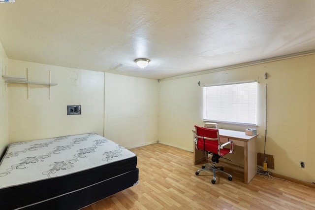 bedroom with a textured ceiling and light hardwood / wood-style floors