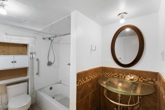 full bathroom with toilet, sink, tile walls, and a textured ceiling