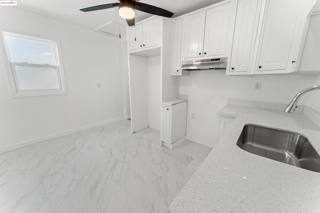 kitchen with light stone counters, sink, white cabinets, and ceiling fan