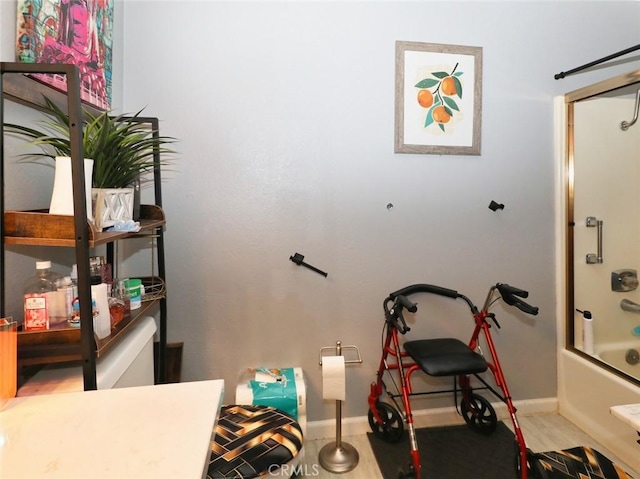 bathroom with hardwood / wood-style floors and shower / bath combination with glass door