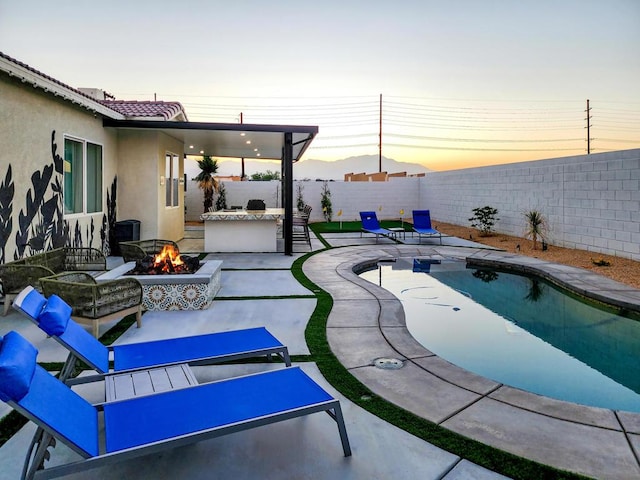 pool at dusk featuring a patio, an outdoor fire pit, and exterior bar