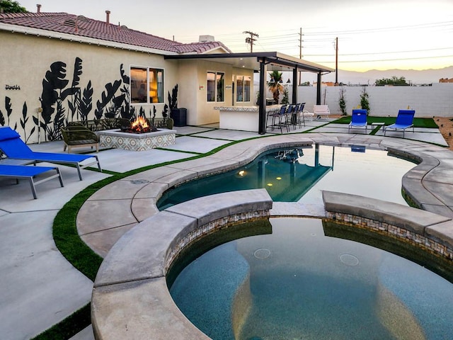 pool at dusk with an in ground hot tub, a bar, a fire pit, and a patio