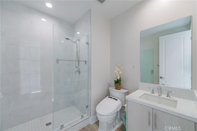 bathroom featuring a shower with door, vanity, and toilet