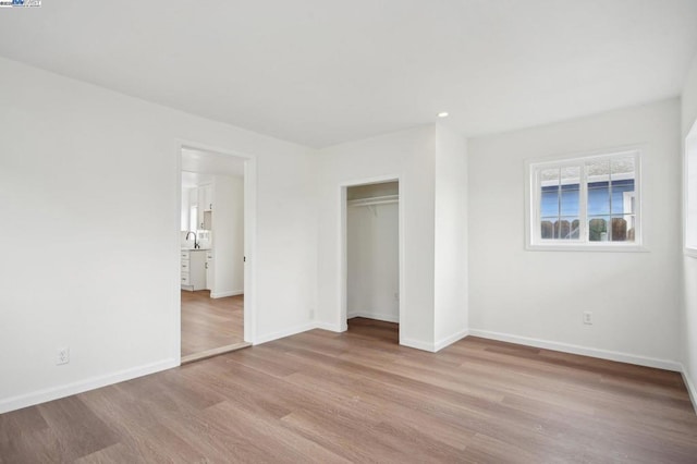 unfurnished bedroom with sink, a closet, and light wood-type flooring