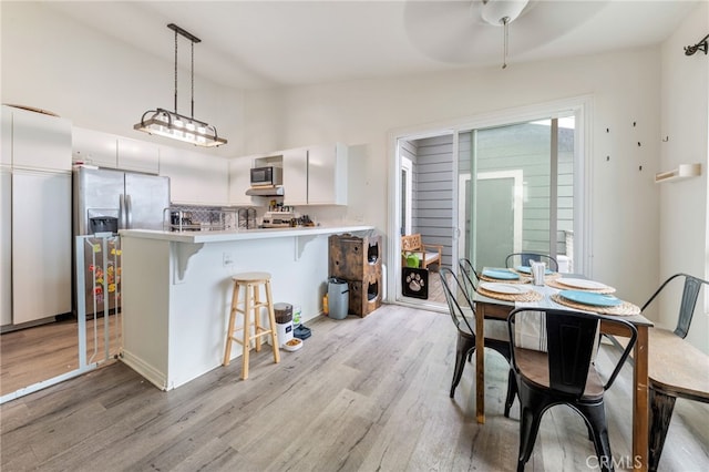 kitchen with a peninsula, a breakfast bar, stainless steel appliances, and light wood-style flooring