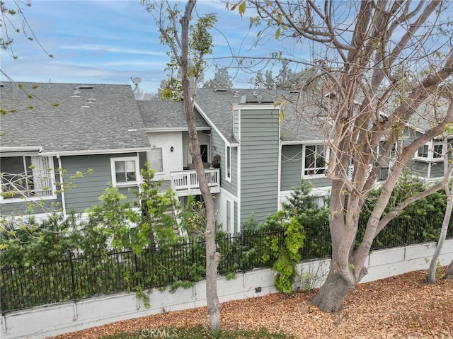 exterior space with a shingled roof, fence, and a balcony