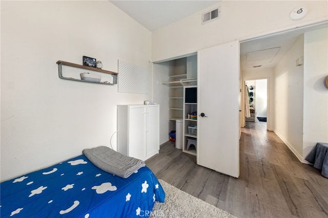 bedroom featuring baseboards, a closet, visible vents, and wood finished floors