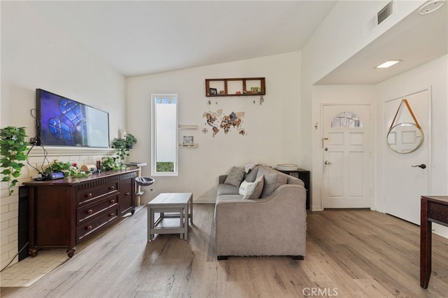 living room featuring visible vents, vaulted ceiling, and light wood finished floors