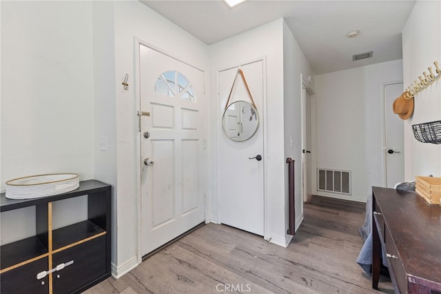 foyer entrance with light wood finished floors, visible vents, and baseboards