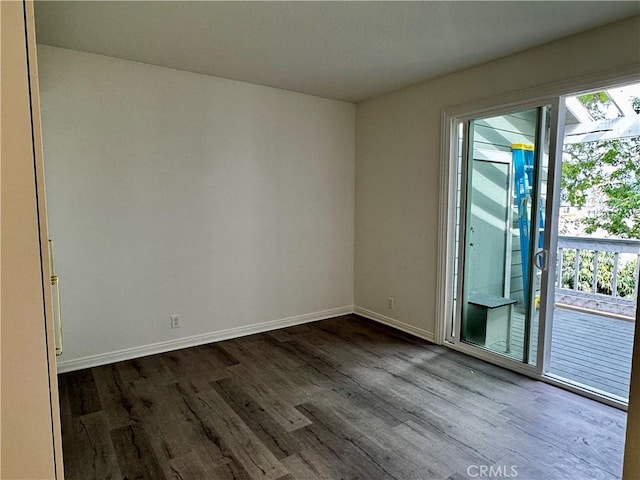 empty room featuring dark wood-style floors and baseboards