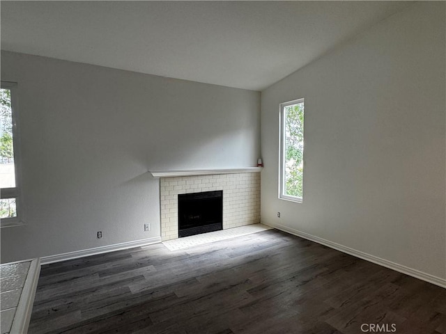 unfurnished living room with lofted ceiling, a fireplace, plenty of natural light, and wood finished floors