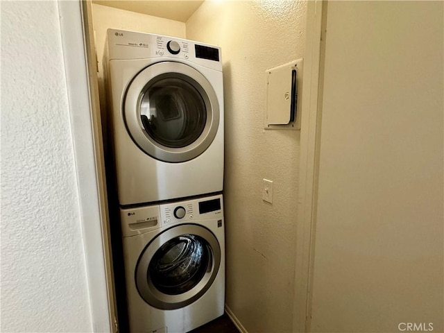 laundry room with stacked washer and dryer, laundry area, and a textured wall