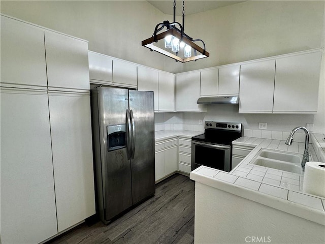 kitchen with dark wood finished floors, tile countertops, stainless steel appliances, a sink, and under cabinet range hood