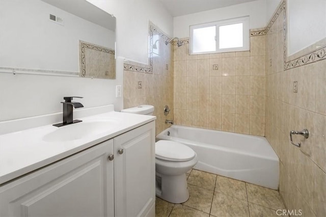 full bathroom with toilet, tiled shower / bath combo, tile walls, tile patterned floors, and vanity