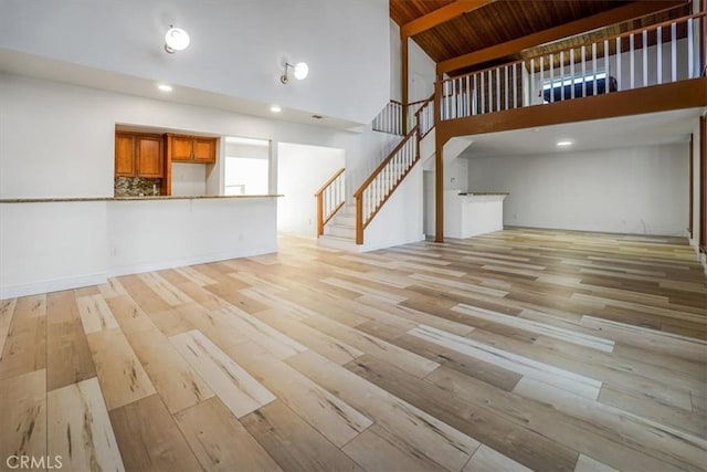 unfurnished living room featuring high vaulted ceiling, light hardwood / wood-style flooring, and wooden ceiling