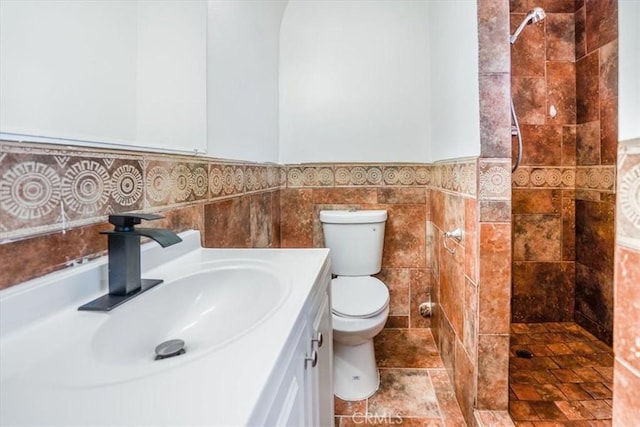 bathroom with a shower, tile walls, toilet, and vanity